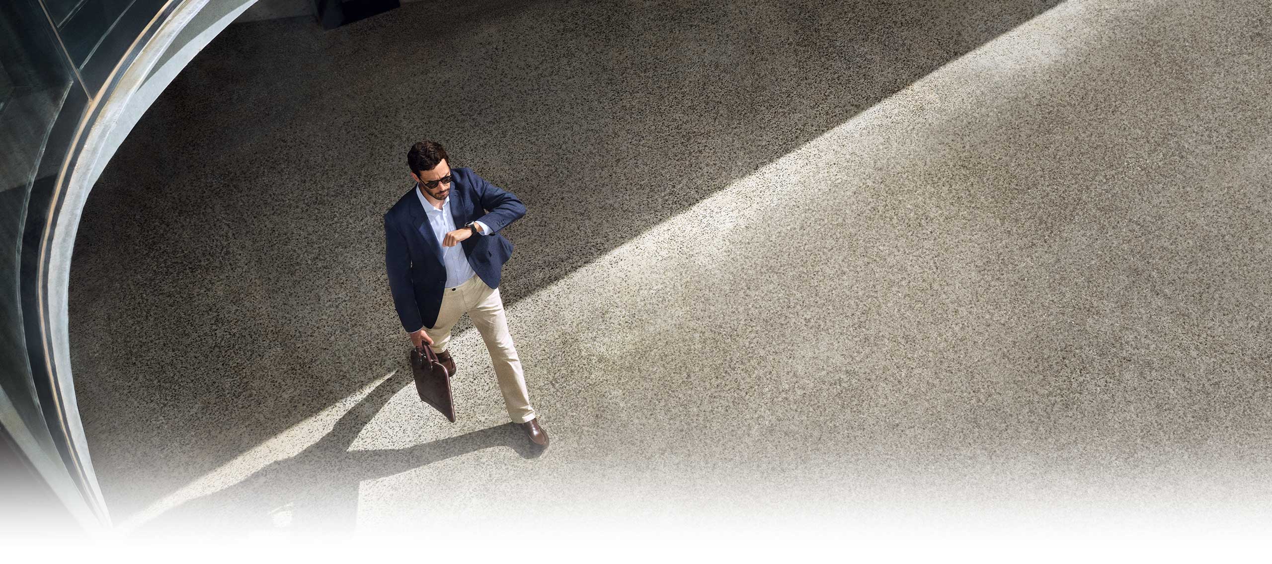 Person in a business casual outfit is looking at his Galaxy Watch8 Classic while walking.